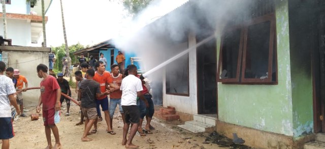 Warga membantu memadamkan api di salah satu rumah warga yang dibakar, foto : Yanti