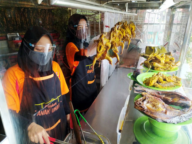 Pekerja di Pondok Pindang Umak, Jalan Demang Lebar Daun Palembang, menggunakan masker dan face shield saat melakukan proses memasak. (Foto. Reno Saputra / Urban Id)