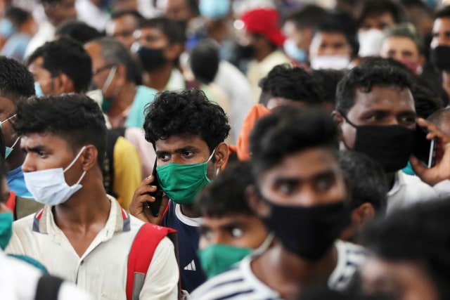 Migran kembali dari kampung halamannya di Uttar Pradesh tiba untuk mengantri untuk dites penyakit virus corona di sebuah stasiun kereta api, di pinggiran Mumbai, India. Foto: Francis Mascarenhas/Reuters