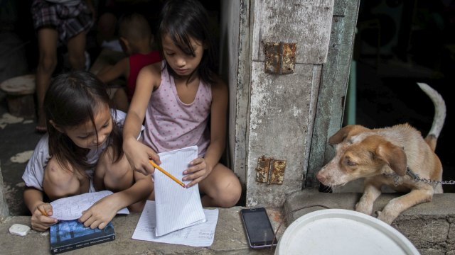 Siswa dan saudara kandung Filipina Shaina dan Yuki Ugal mengerjakan tugas sekolah untuk kelas online di rumah kumuh mereka, di tengah wabah penyakit coronavirus (COVID-19), di Tondo, Manila, Filipina, Selasa (6/10/2020). Foto: ELOISA LOPEZ/REUTERS