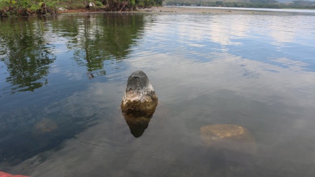 Menhir yang dipercaya sebagai batu perempuan, sedangkan batu kecil di sampingnya dipercaya sebagai batu anak yang berada di dasar Danau Sentani.. (Dok Balai Arkeologi Papua/Hari Suroto)