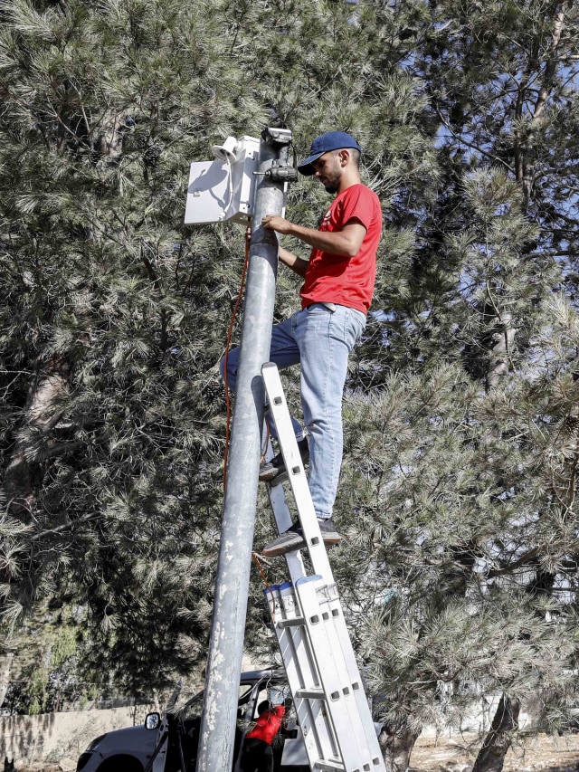 Seorang pekerja memasang sistem pengawasan video untuk mengawasi pemukim Israel. Foto: MUSSA ISSA QAWASMA/REUTERS