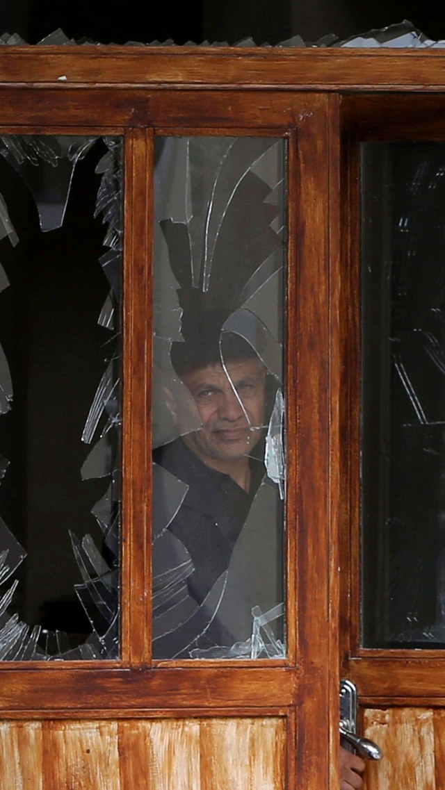 Seorang pria terlihat dari jendela sebuah bangunan yang rusak, akibat konflik militer di wilayah Nagorno-Karabakh yang memisahkan diri, di Stepanakert, Kamis (8/10). Foto: Hayk Baghdasaryan/Photolure via REUTERS