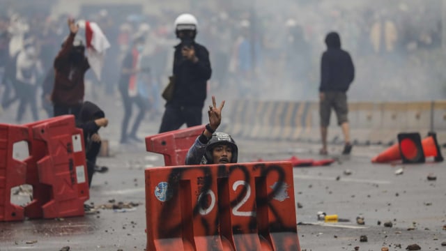 Seorang demonsran berlindung di balik pembatas jalan saat unjuk rasa menolak Omnibus Law di Jakarta, Kamis (8/10/2020). Foto: Willy Kurniawan/REUTERS