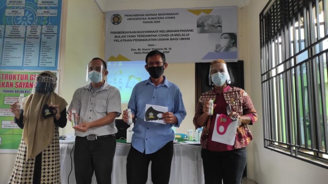 Ketua Tim Pengabdian LPPM USU, bersama Lurah Padang Bulan dan komunitas Ibu PKK menunjukkan hasil pelatihan usaha berupa masker dan hand sanitizer