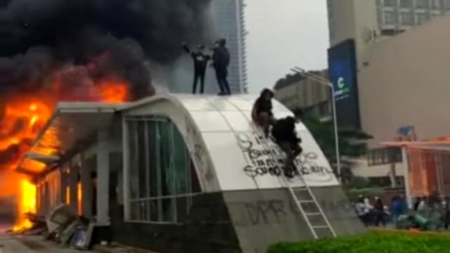 Pengujuk rasa menaiki halte transjakarta yang dibakar saat unjuk rasa, di Jakarta, Kamis (8/10). Foto: Instagram/@narkoba-metro