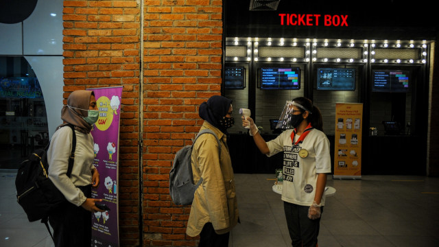 Petugas memeriksa suhu tubuh pengunjung yang akan menonton film di salah satu bioskop di Kota Bandung, Jawa Barat, Jumat (9/10). Foto: Raisan Al Farisi/ANTARA FOTO