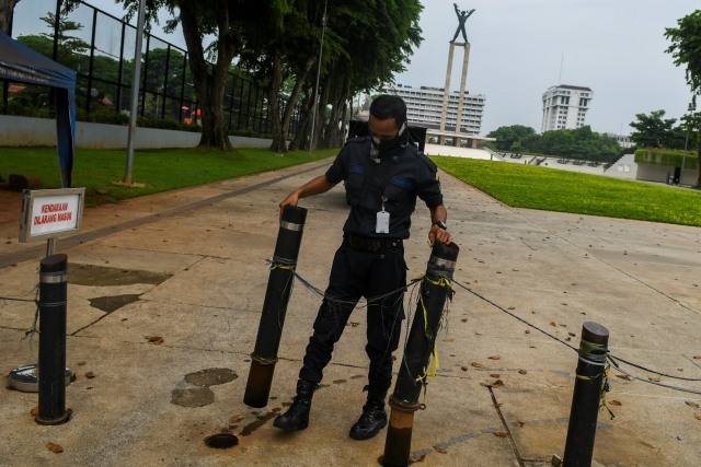 Petugas keamanan menutup kawasan Taman Lapangan Banteng, Jakarta, Minggu (11/10).  Foto: Galih Pradipta/ANTARA FOTO
