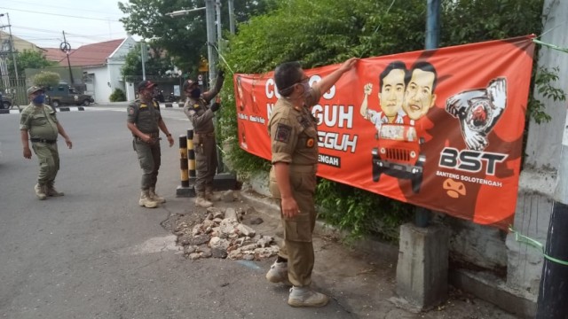 Satpol PP menertibkan APK milik pasangan calon Wali Kota Solo Gibran-Teguh. Foto: kumparan