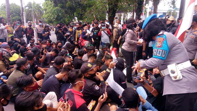 Polwan membagikan roti dan air mineral kepada para peserta demo penolakan Omnibus Law UU Cipta Kerja di Kota Bitung, Sulawesi Utara