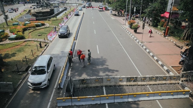 Pengendara mobil melintas di dekat jalan yang ditutup sebelum aksi unjuk rasa menolak UU Omnibus Law Cipta Kerja di Jalan Merdeka Barat, Jakarta, Selasa (13/9). Foto: Aditia Noviansyah/kumparan
