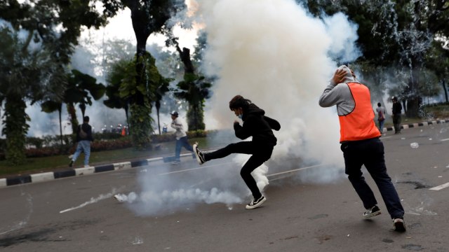 Seorang demonstran menendang tabung gas air mata kembali ke polisi, selama bentrokan di tengah demo tolak Omnibus Law, di Jakarta, Selasa (13/10). Foto: Willy Kurniawan/REUTERS