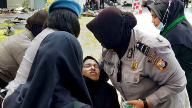 Polwan saat membantu mahasiswa yang pingsan dalam aksi penolakan UU Cipta Kerja di Ternate, Selasa 13 Oktober 2020. Foto: Istimewa