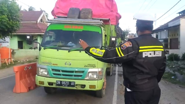 Seorang Polisi yang tergabung dalam Satgas COVID-19 Sulteng memberhentikan salah satu kendaraan yang hendak masuk wilayah Kota Palu, di Pos COVID-19 Pantoloan. Foto: Istimewa  
