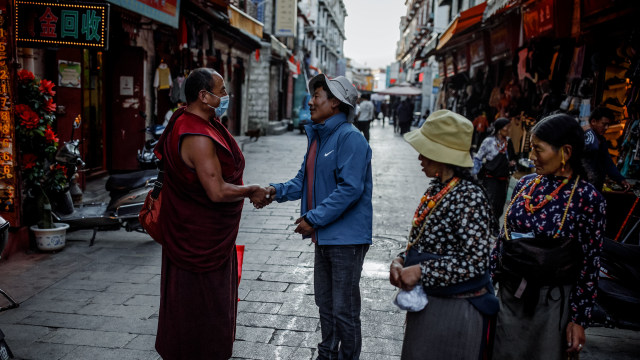 Seorang pria berbicara dengan seorang biksu Tibet di sebuah gang pasar di kota tua Lhasa, Tibet, China, Rabu (14/10/2020). Foto: THOMAS PETER/REUTERS