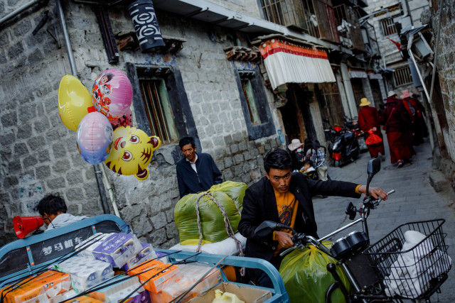 Orang-orang mengangkut barang di gang dekat pasar di kota tua Lhasa, Tibet, China, Rabu (14/10/2020). Foto: THOMAS PETER/REUTERS