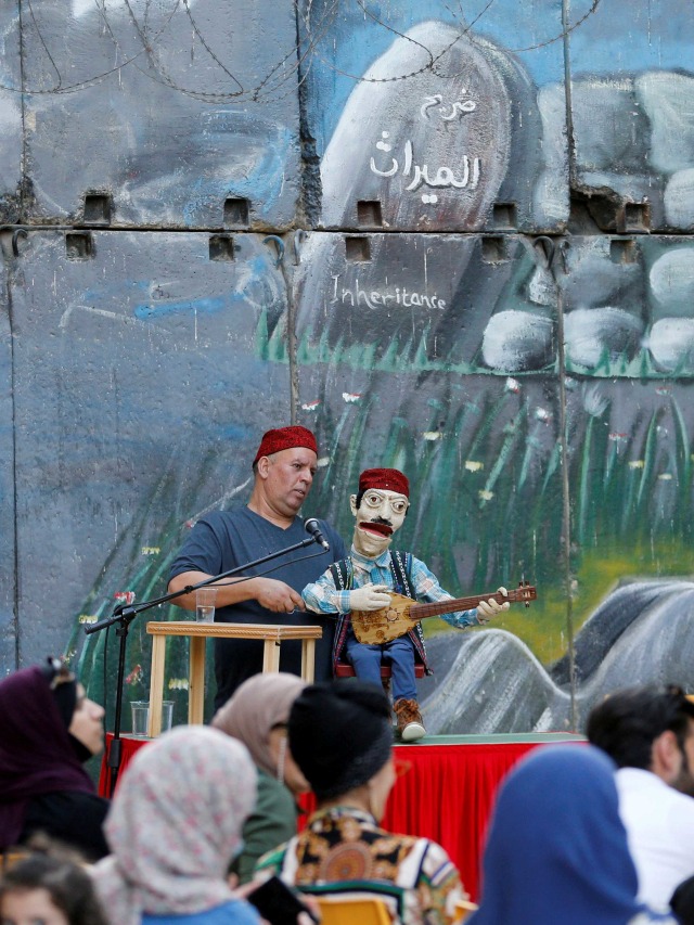 Seorang seniman Palestina tampil dengan boneka saat pertunjukan warisan di Hebron, Tepi Barat, Palestina. Foto: Mussa Qawasma/Reuters