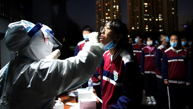 Petugas medis dengan APD melakukan swab tes virus corona kepada warga di Qingdao, provinsi Shandong, China. Foto: cnsphoto via REUTERS