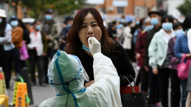 Petugas medis dengan APD melakukan swab tes virus corona kepada warga di China. Foto: cnsphoto via REUTERS