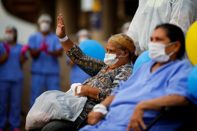 Pasien Alzira Neves, 53, memberi isyarat di depan rumah sakit lapangan sementara di Stadion Mane Garrincha, Brasillia, Brasil, Jumat (15/10/2020). Foto: ADRIANO MACHADO/REUTERS