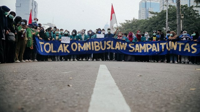 Massa dari BEM SI membentangkan spanduk saat berunjuk rasa menolak Omnibus Law di kawasan Patung Kuda, Jalan Medan Merdeka Barat, Jakarta, Jumat (16/10) Foto: Aditia Noviansyah/kumparan