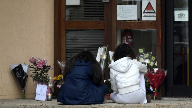 Sejumlah murid duduk di depan sebuah sekolah menengah di Conflans Saint-Honorine, Prancis, lokasi seorang guru dipenggal, Jumat (16/10). Foto: Bertrand GUAY / AFP