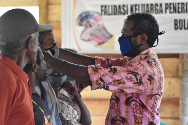 Pemasangan masker oleh kepala kampung kepada masyarakatnya