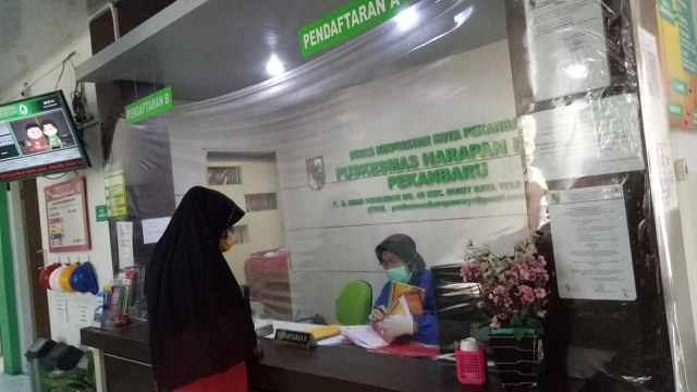 SEORANG warga saat berobat di Puskesmas Bukit Raya, Pekanbaru, dengan penerapan protokol kesehatan.  