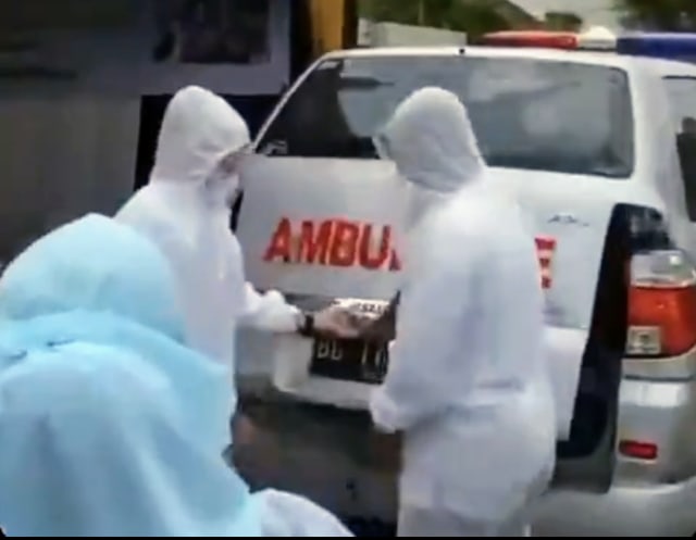 Petugas berseragam APD lengkap saat menyerahkan seserahan yang dibawa menggunakan ambulans. (foto: istimewa)