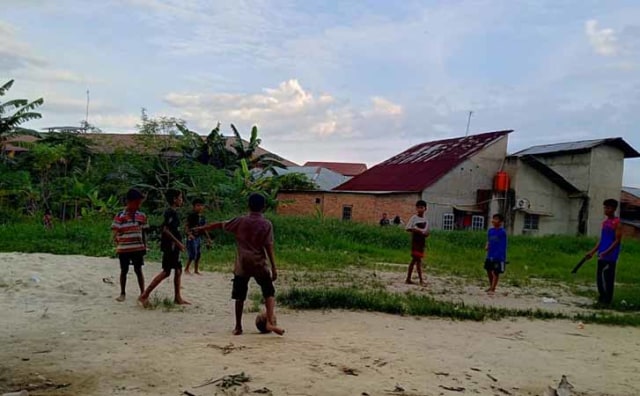 YUSUF (15), anak pengungsi Rohingnya (kanan), bermain sepak bola dengan anak-anak di sekitar tempat penampungan mereka di Pekanbaru. 