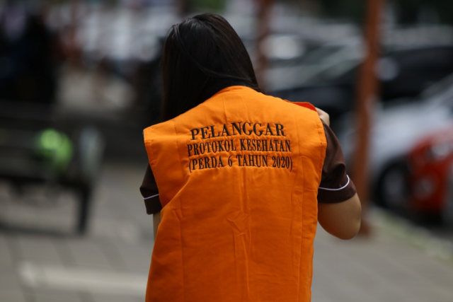 Salah seorang warga mengenakan rompi pelanggar sanksi sosial saat razia Perda AKB Pencegahan dan Pengendalian COVID-19 di Kota Padang. Foto: Humas Satpol PP Padang. 