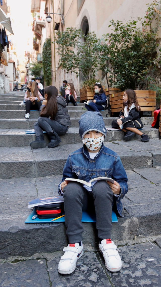 Sejumlah murid mengikuti pembelajaran dengan menjaga jarak sosial di tangga publik, di Napoli, Italia, Rabu (21/10). Foto: Ciro De Luca/REUTERS