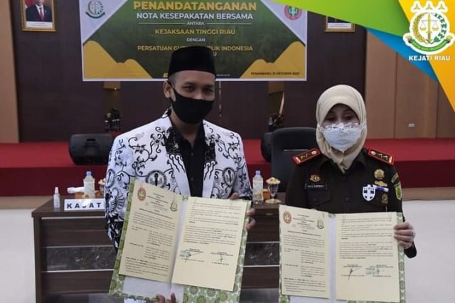 KEPALA Kejaksaan Tinggi (Kajati) Riau, Mia Amiati (kanan) dan Ketua PGRI Riau, M Syafi'i, memperlihatkan MoU sudah ditandatangani di antara keduanya, Rabu (21/10/2020). 
