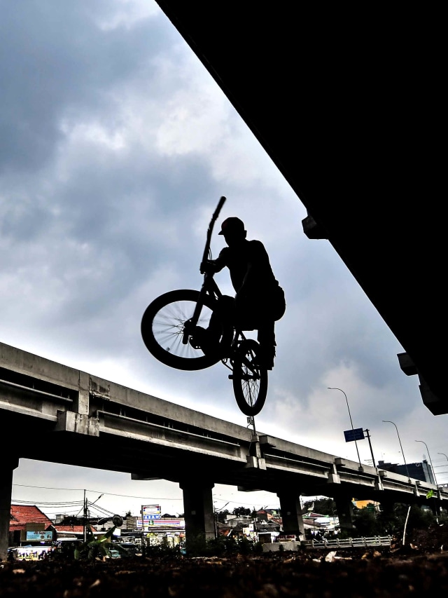 Siluet pesepeda saat melakukan lompatan saat melakukan uji coba lokasi pembangunan trek sepeda di kolong Tol Becakayu, Cipinang Melayu, Jakarta Timur. Foto: Muhammad Adimaja/Antara Foto