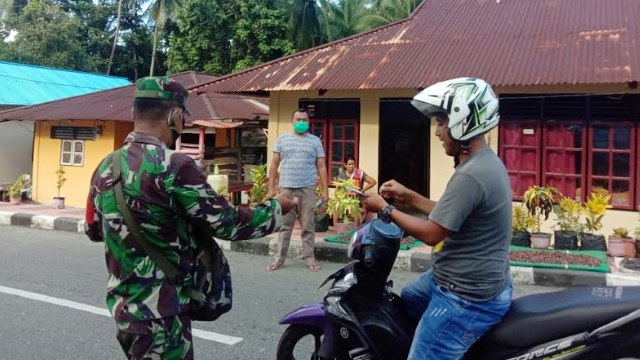 Pihak TNI membagikan masker gratis untuk pengendara di jalan