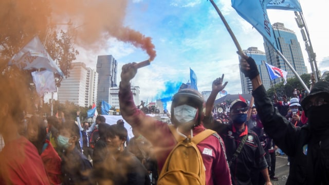 Massa aksi menyalakan flare asap saat unjuk rasa menolak Omnibus Law, di kawasan Jalan Merdeka Barat, Jakarta, Kamis (22/10). Foto: M Risyal Hidayat/ANTARA FOTO