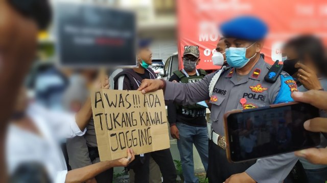 Polisi menunjukkan poster yang dibawa pelajar saat demo Omnibus Law di Denpasar, Bali - ACH