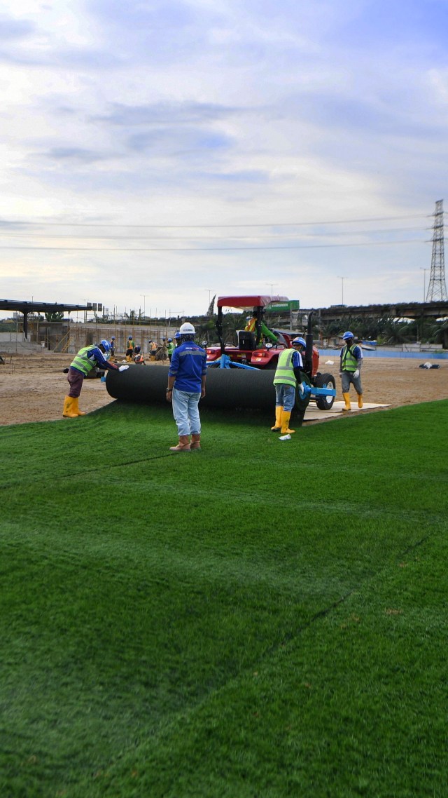 Pekerja menyelesaikan pemasangan rumput untuk lapangan latih di Kompleks Stadion Utama Jakarta International Stadium (JIS), Jakarta, Jumat (23/10). Foto: Puspa Perwitasari/ANTARA FOTO