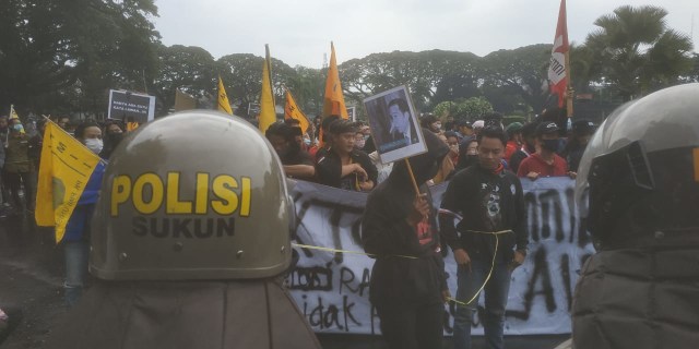 Demonstran membawa poster Jokowi Berhidung Mancung saat aksi unjuk rasa menolak Omnibus Law di Malang, Jumat (23/10).Foto/Azmy