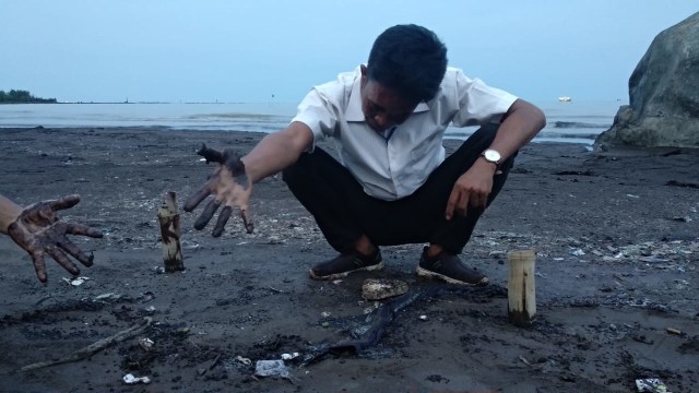 Sejumlah pengelola pantai Karangsong Indramayu memperlihatkan ceceran hitam mirip minyak mentah yang berada di bibir pantai. (Tomi Indra)