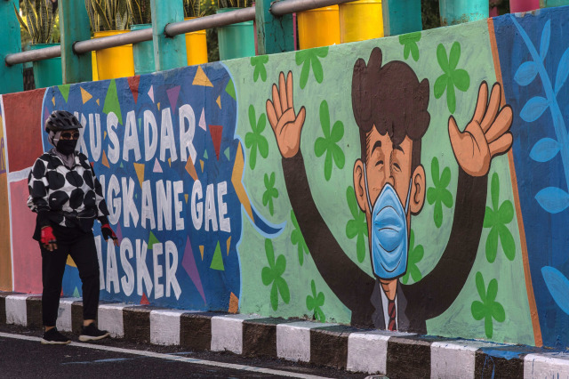 Mural yang mengajak warga untuk memakai masker di tengah pandemi COVID-19 di Surabaya. Foto: Juni Kriswanto/AFP