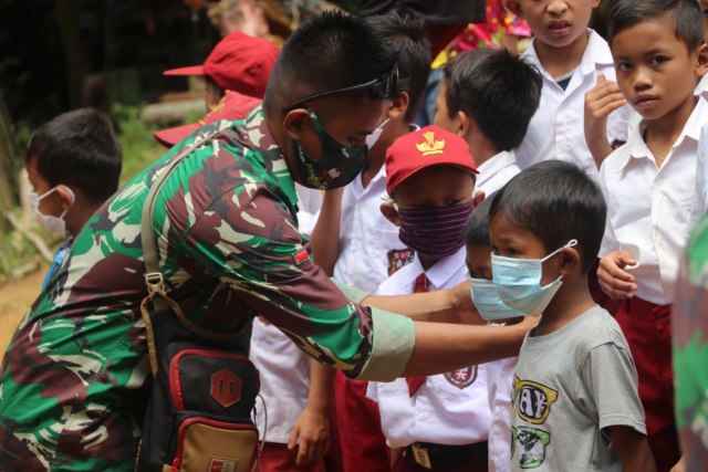 Personel Satgas TMMD Sintang memasangkan masker pada anak-anak perbatasan. (Foto; Pendim Sintang)