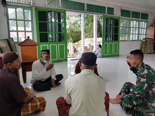 Personel TNI berbincang dengan pengurus Masjid Al Mutaqin, Sugiana. Di kesempatan itu, ia mengungkapkan rasa senangnya atas hadirnya TMMD di desanya. (Foto: Pendim Sintang)