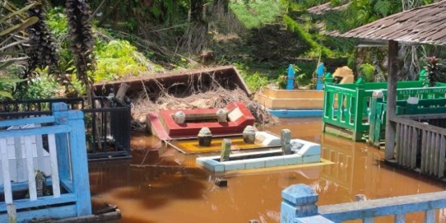 Kubur berjubin merah yang terbongkar dan terendam banjir.(FOTO: Dokumen Warga)