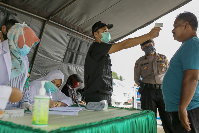 Petugas memeriksa suhu tubuh penumpang dari angkutan umum. Foto: Abdul Hadi/acehkini
