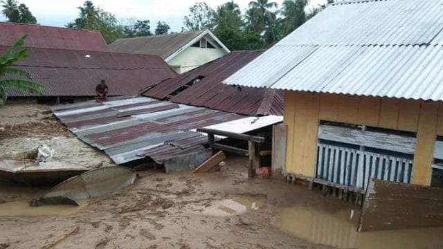 Salah satu warga yang masih berada di atas rumah yang dipenuhi lumpur akibat banjir di Desa Bangga, Kecamatan Dolo Selatan, Kabupaten Sigi, Sulteng, pada 2019. Foto: Istimewa