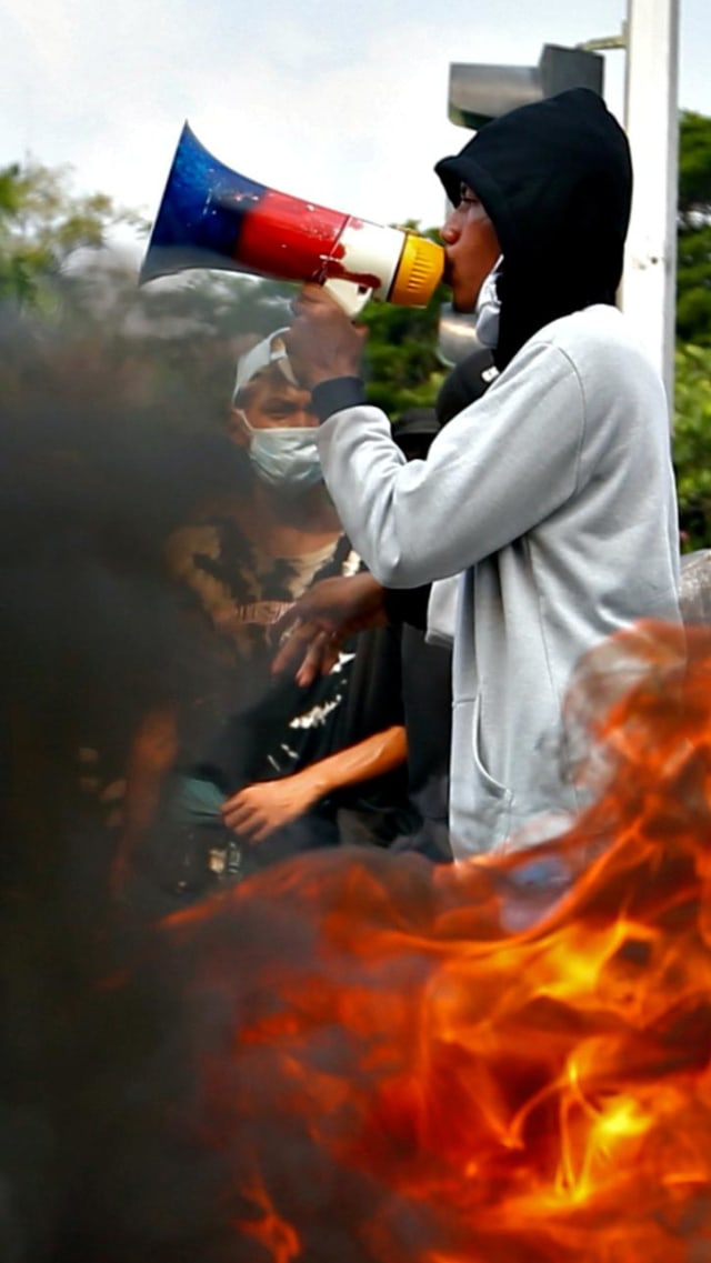 Mahasiswa membakar ban saat memprotes Undang-Undang Cipta Kerja atau Omnibus Law di Jakarta, Rabu (28/10). Foto: Ajeng Dinar Ulfiana/REUTERS