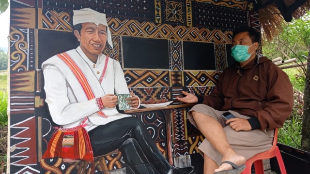 Lukisan Presiden Jokowi yang mengenakan pakaian adat Mamasa sambil ngopi dipajang di pintu masuk desa wisata Tondok Bakaru. Foto: Frendy/sulbarkini