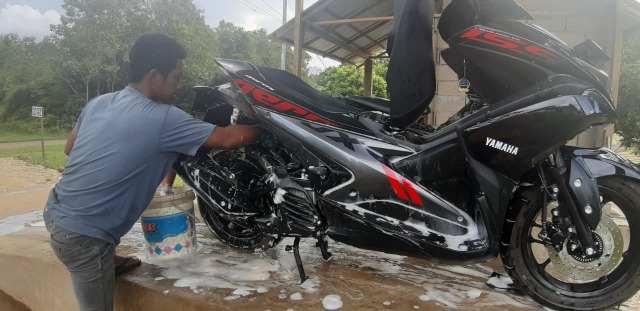 Adi Rahmadi (22) Tampak sedang membersihkan sepeda Motor