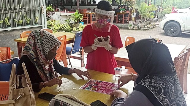 Karyawan salah satu rumah makan di Kabupaten Minahasa Utara, melayani pelanggan menggunakan masker, face shield dan sarung tangan untuk memenuhi protokol kesehatan ketat
